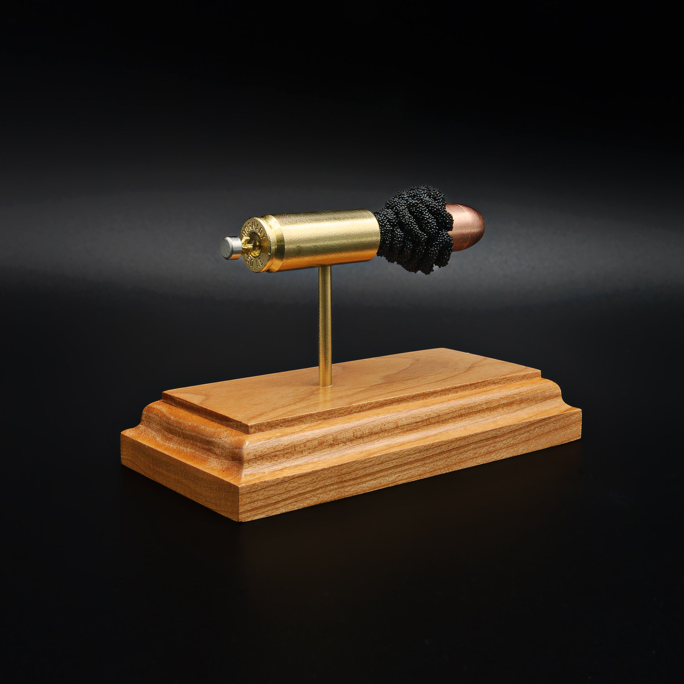 Rear view of a .50 Action Express Hornady Custom 300gr XTP cartridge anatomy display showing the cartridge case head, primer cup, anvil, simulated powder, and projectile on a cherry wood base.