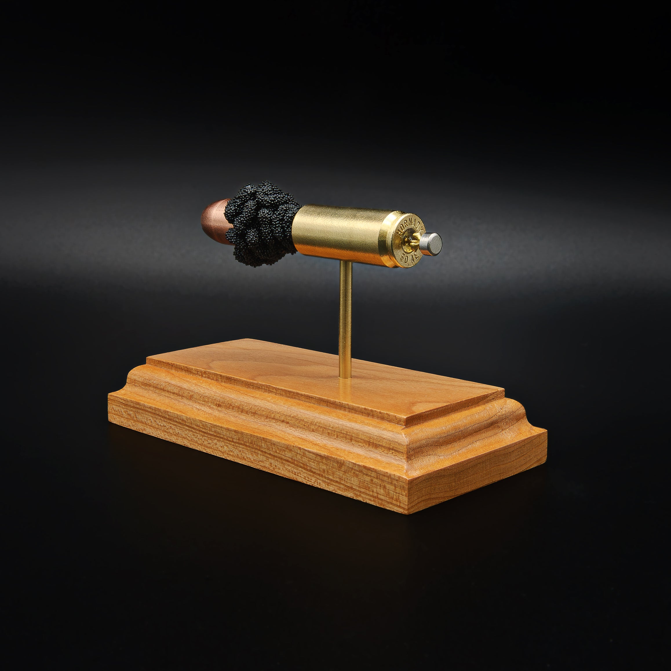 Angled rear view of a .50 Action Express Hornady Custom 300gr XTP cartridge anatomy display featuring the primer cup, anvil, cartridge case, simulated powder, and projectile on a cherry wood base.