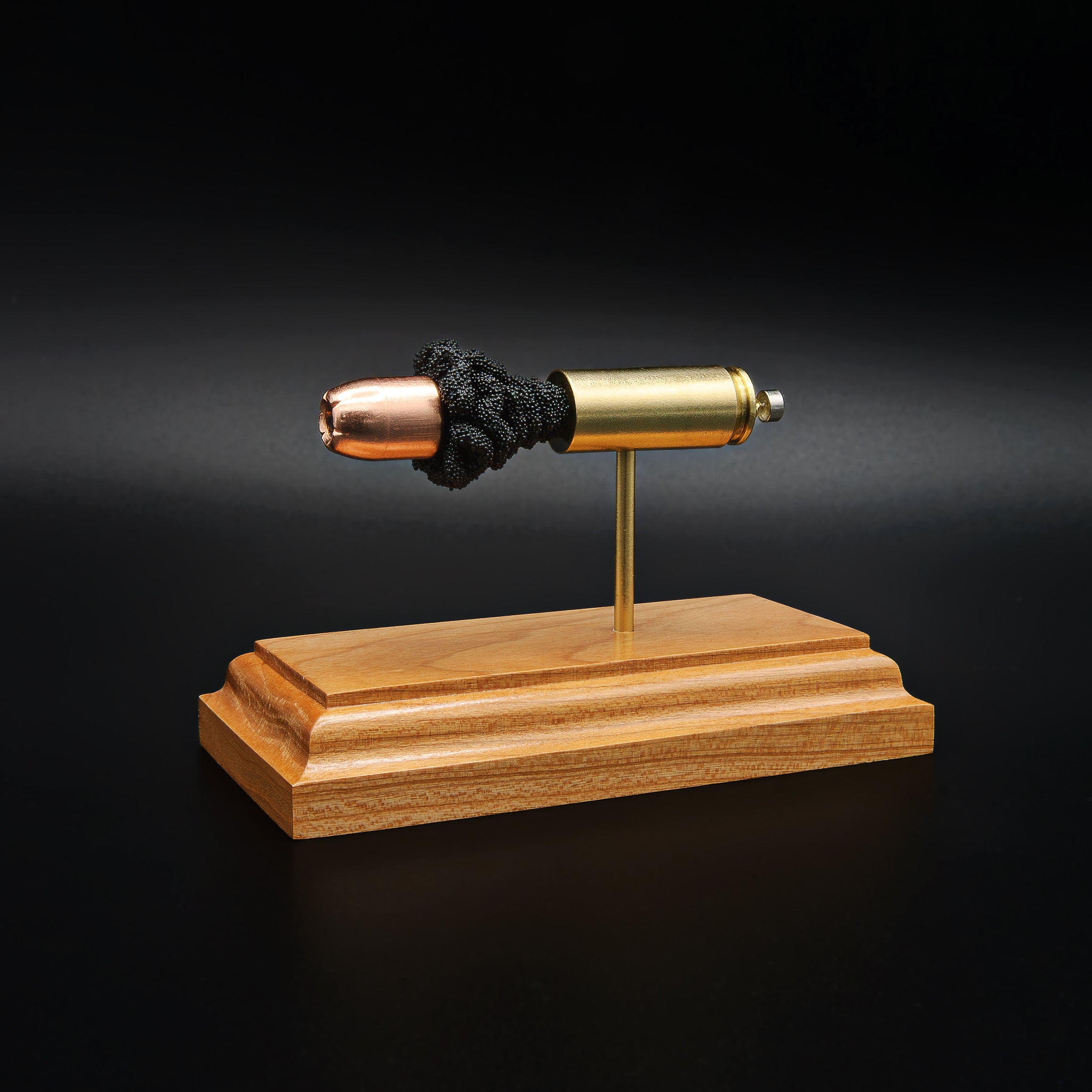 Opposite side view of a .50 Action Express Hornady Custom 300gr XTP cartridge anatomy display showing the primer cup, anvil, cartridge case, simulated powder, and projectile on a cherry wood base.