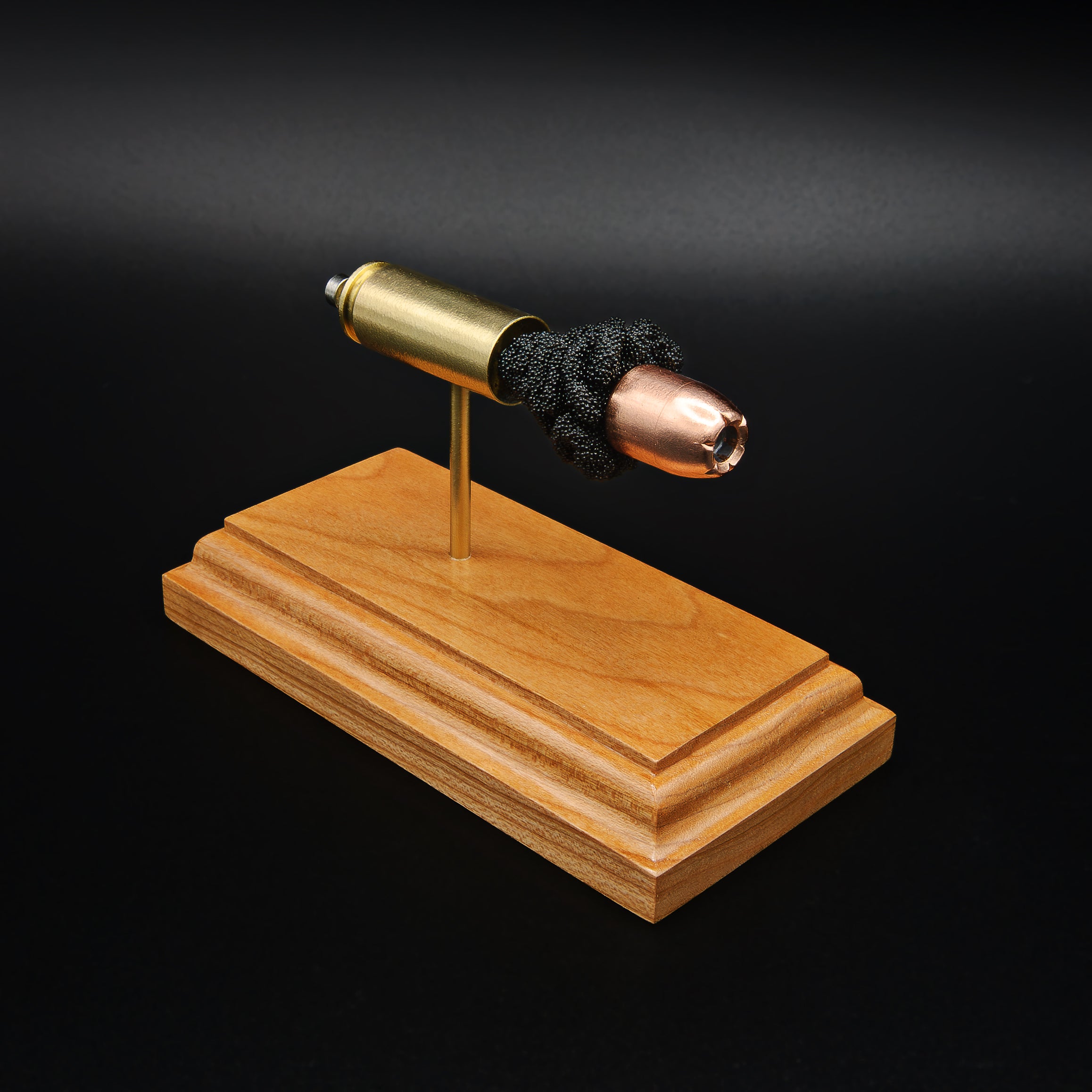 High angled view of a .50 Action Express Hornady Custom 300gr XTP cartridge anatomy display highlighting the projectile, simulated powder, cartridge case, primer cup, and anvil on a cherry wood base.