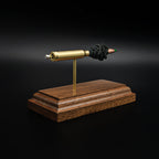 Rear left angle of a 5.56×45mm NATO M855 Green Tip cartridge anatomy display showing the cartridge head, primer assembly, and separated internal components on a walnut base.