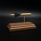 Rear right angle of a 5.56×45mm NATO M855 Green Tip cartridge anatomy display highlighting the exposed cartridge components and green tip projectile on a walnut base.
