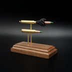 Front-right three-quarter view of a handcrafted 5.56x45 NATO SS109 Green Tip Comparison Series showing the expanded cartridge components alongside the complete live cartridge on a walnut display base.