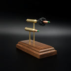 Front-left angle of an inert 5.56x45 NATO SS109 Green Tip Comparison Series display highlighting the exploded cartridge, simulated powder, complete cartridge, and solid walnut presentation base.