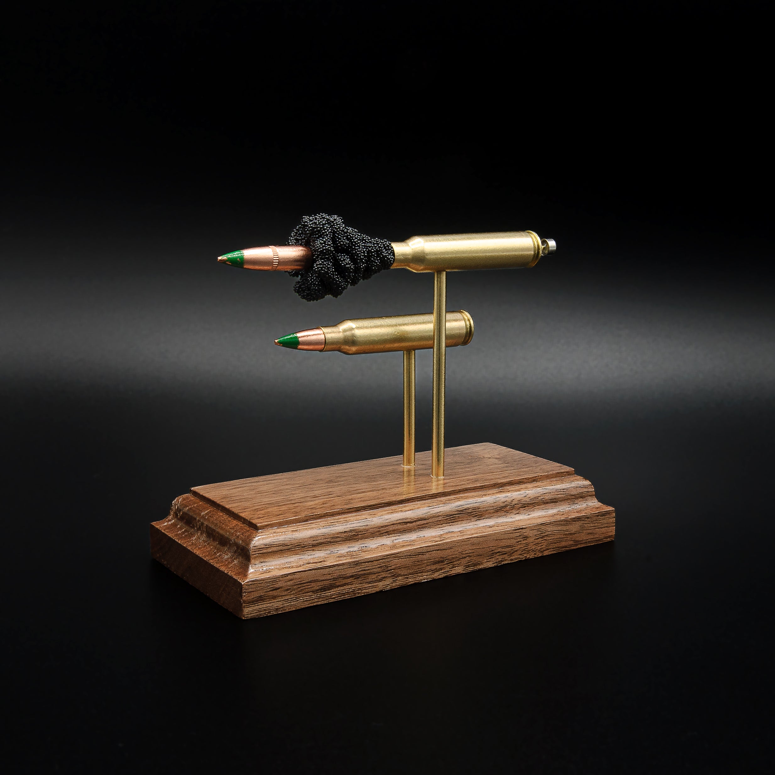 Left side profile of a 5.56x45 NATO SS109 Green Tip Comparison Series display featuring an exploded cartridge with simulated powder above a complete live cartridge on a walnut presentation base.
