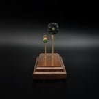 End-on view of a 5.56x45 NATO SS109 Green Tip Comparison Series display showing the pointed green tip projectiles, exposed simulated powder, and handcrafted walnut wood base.