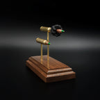 Front-left perspective of a handcrafted 5.56x45 NATO SS109 Green Tip Comparison Series with an exploded cartridge displayed above a complete live cartridge, mounted on an elegant walnut wood presentation base.