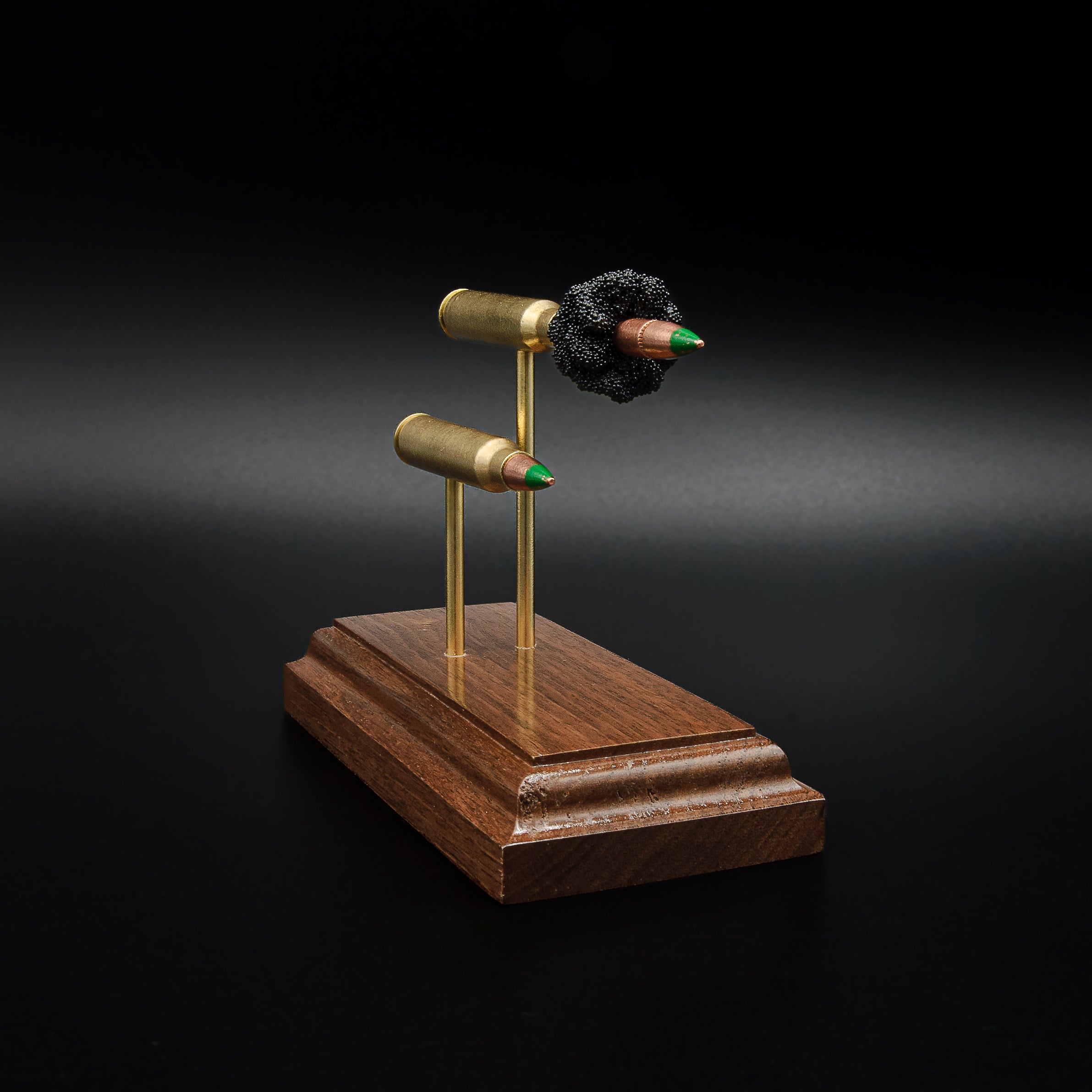 Front-left perspective of a handcrafted 5.56x45 NATO SS109 Green Tip Comparison Series with an exploded cartridge displayed above a complete live cartridge, mounted on an elegant walnut wood presentation base.