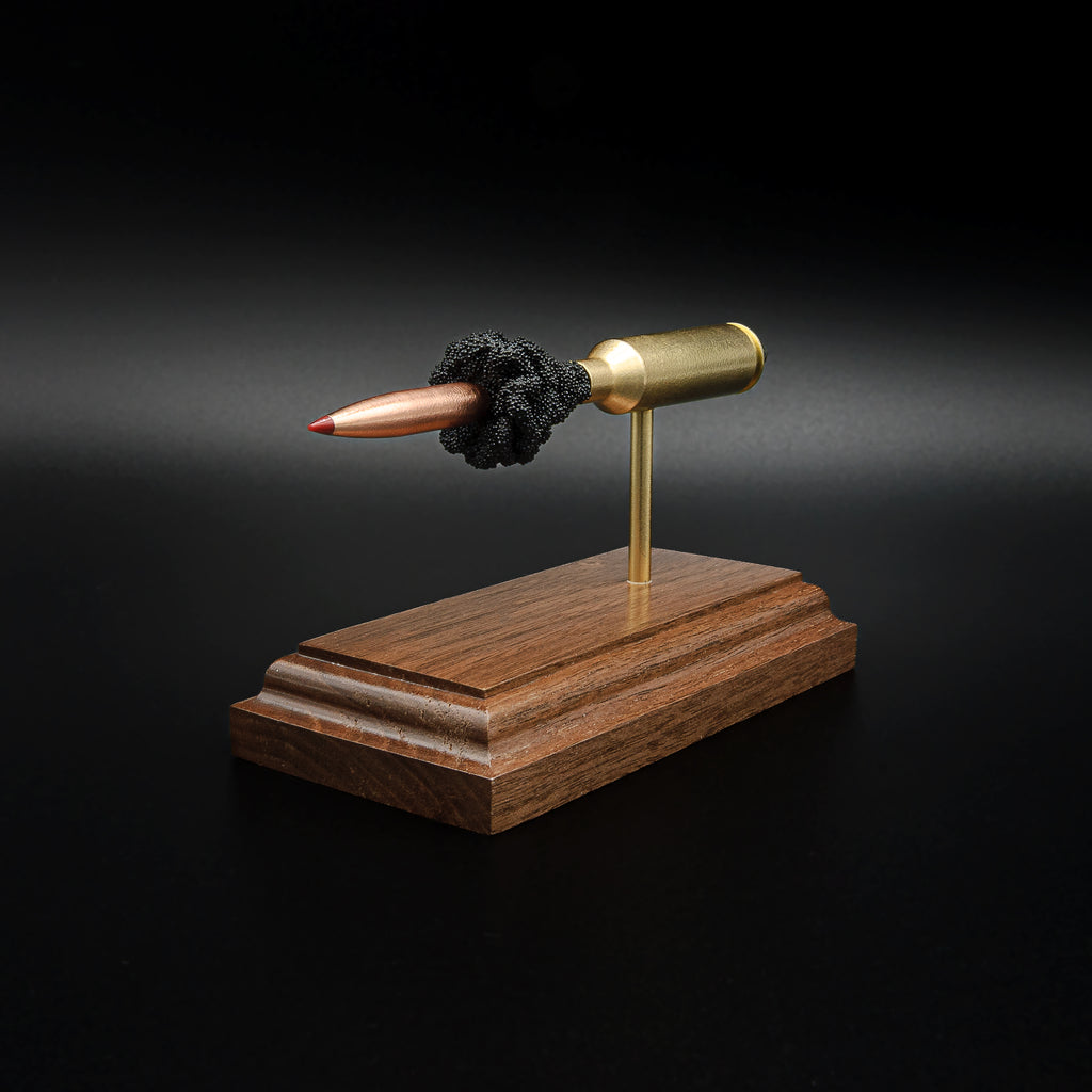 Front-right perspective of a handcrafted 6.5 PRC exploded ammunition display highlighting the Hornady 147gr ELD-M Match bullet, brass case, exposed simulated powder, and walnut display base.