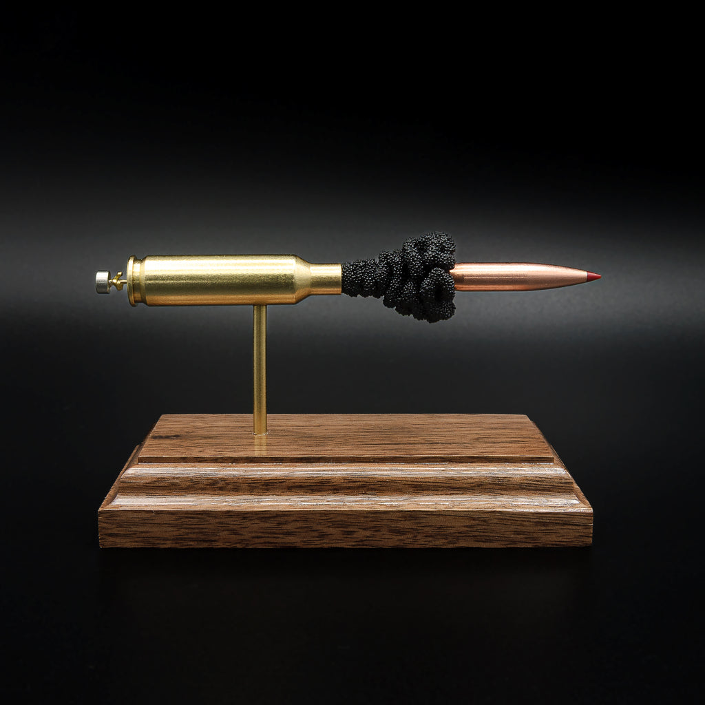 Front profile of a handcrafted 6.5 Creedmoor exploded cartridge display featuring a Hornady 143gr ELD-X bullet with simulated powder on a walnut wood base.