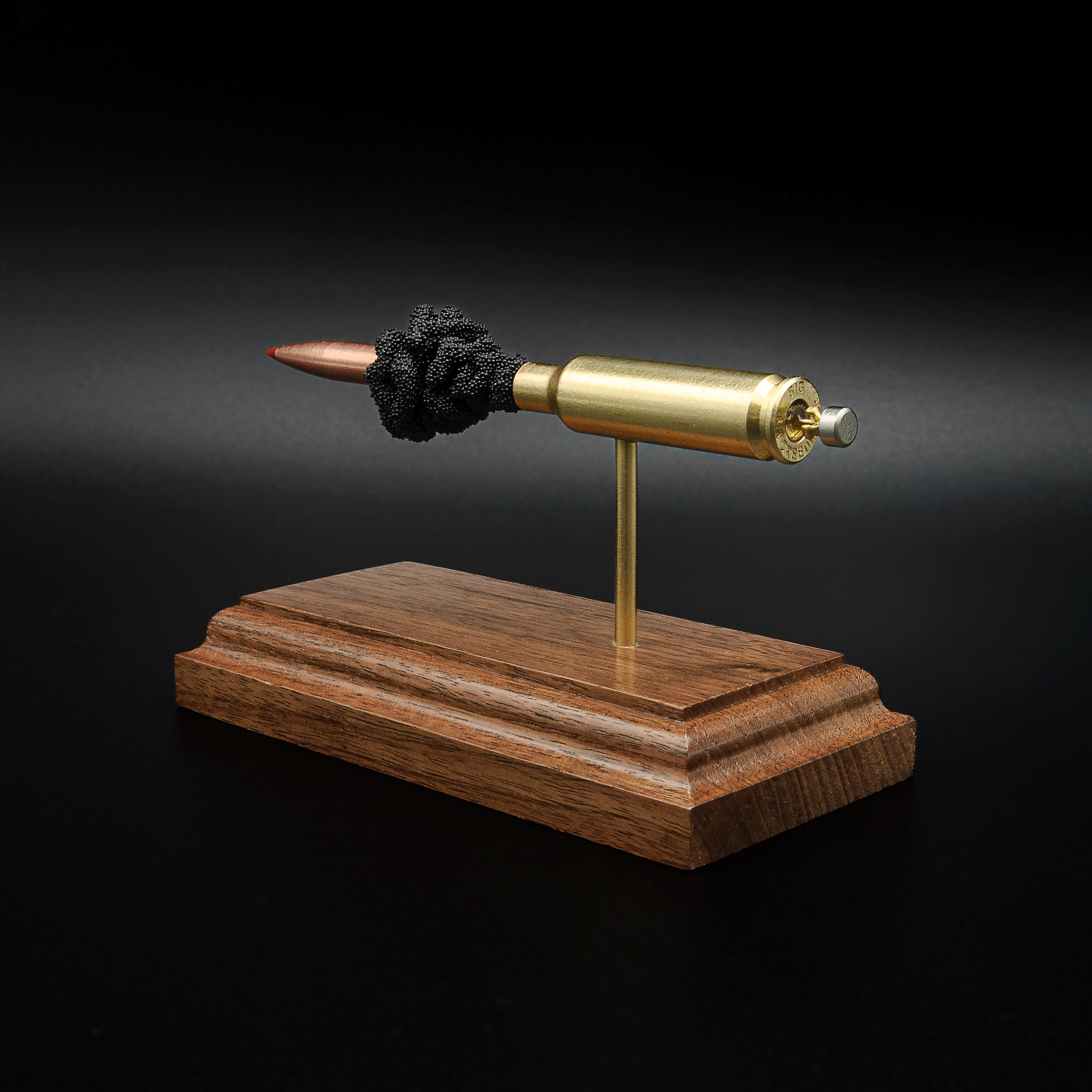 Close rear perspective of a 6.5 Creedmoor anatomy display highlighting the cartridge base, primer details, brass case, and handcrafted walnut base.