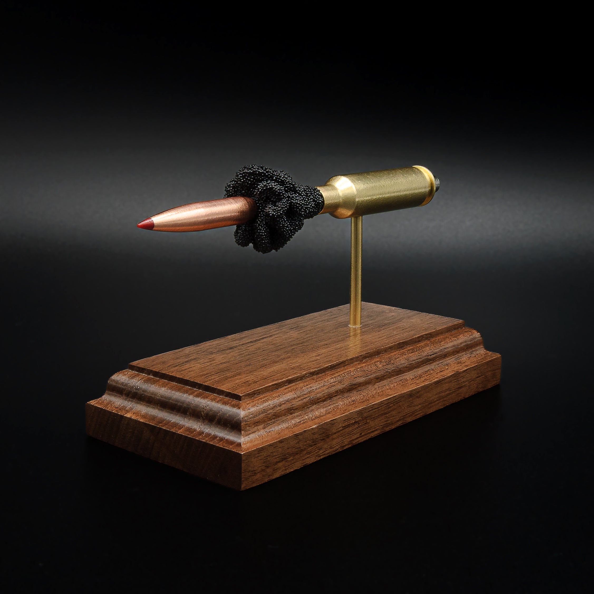 Angled front view of a handcrafted 6.5 Creedmoor exploded cartridge display showcasing the Hornady 143gr ELD-X bullet, exposed powder column, brass case, and walnut display base.