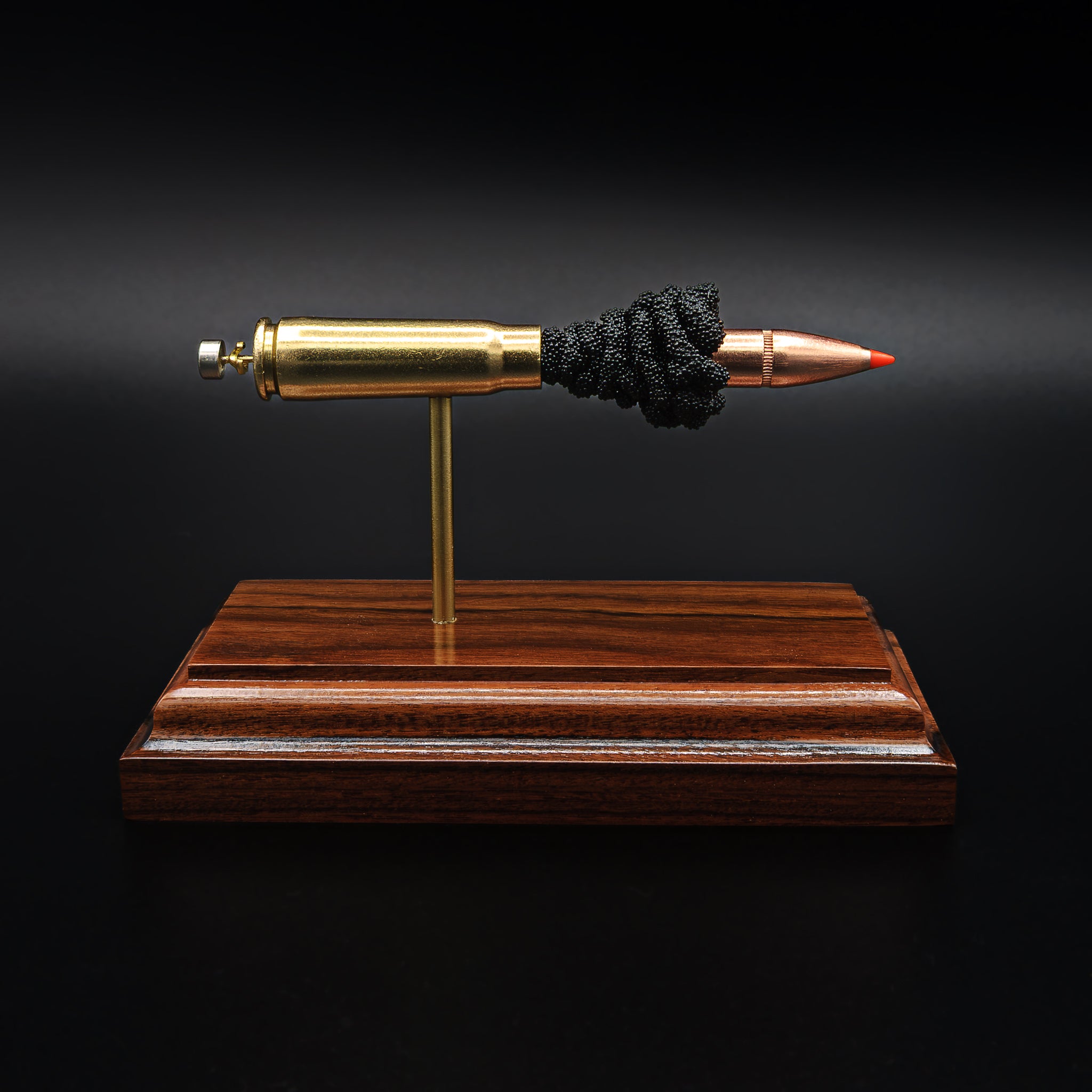 Side view of a 7.62x39 cartridge model mounted on a dark rosewood base, showing each component separated and supported by metal rods