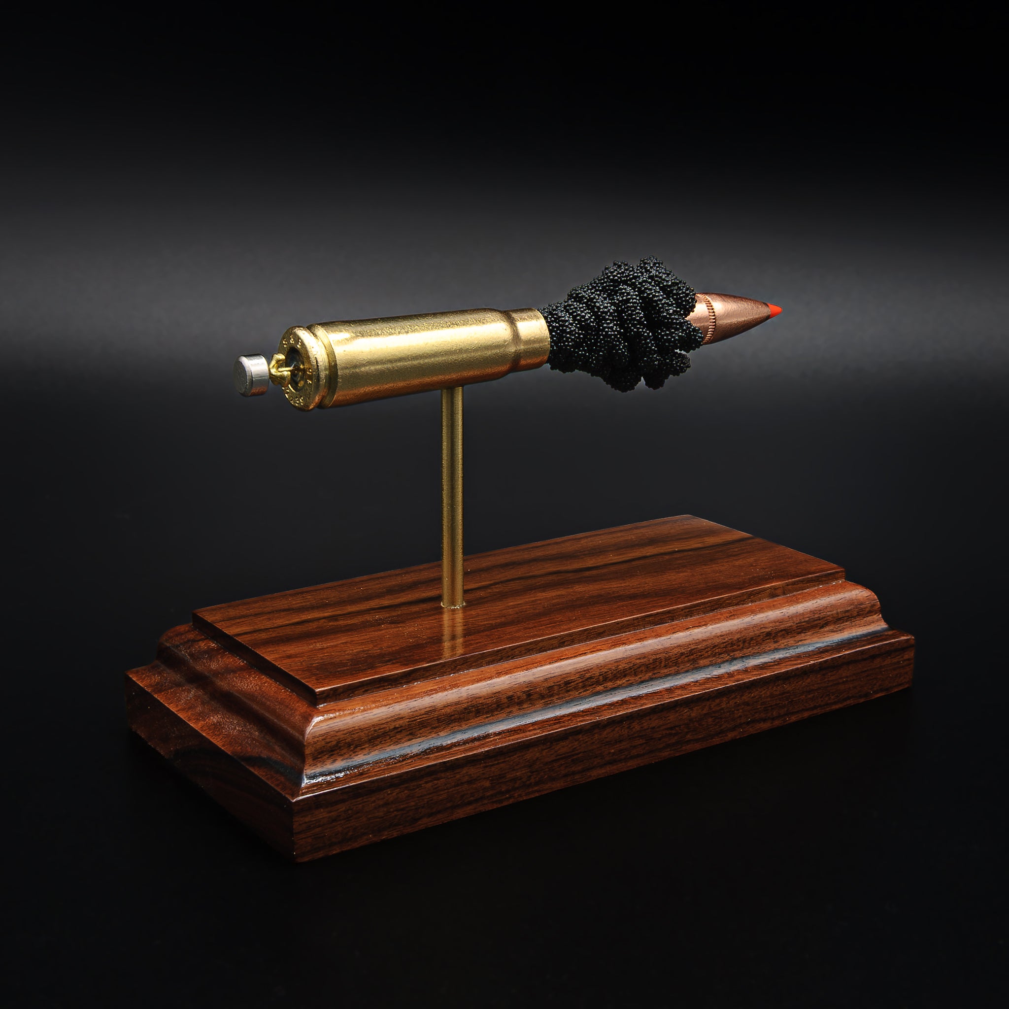 Angled view of a 7.62x39 cartridge display on a rosewood base, highlighting the bullet tip, brass casing, and internal structure