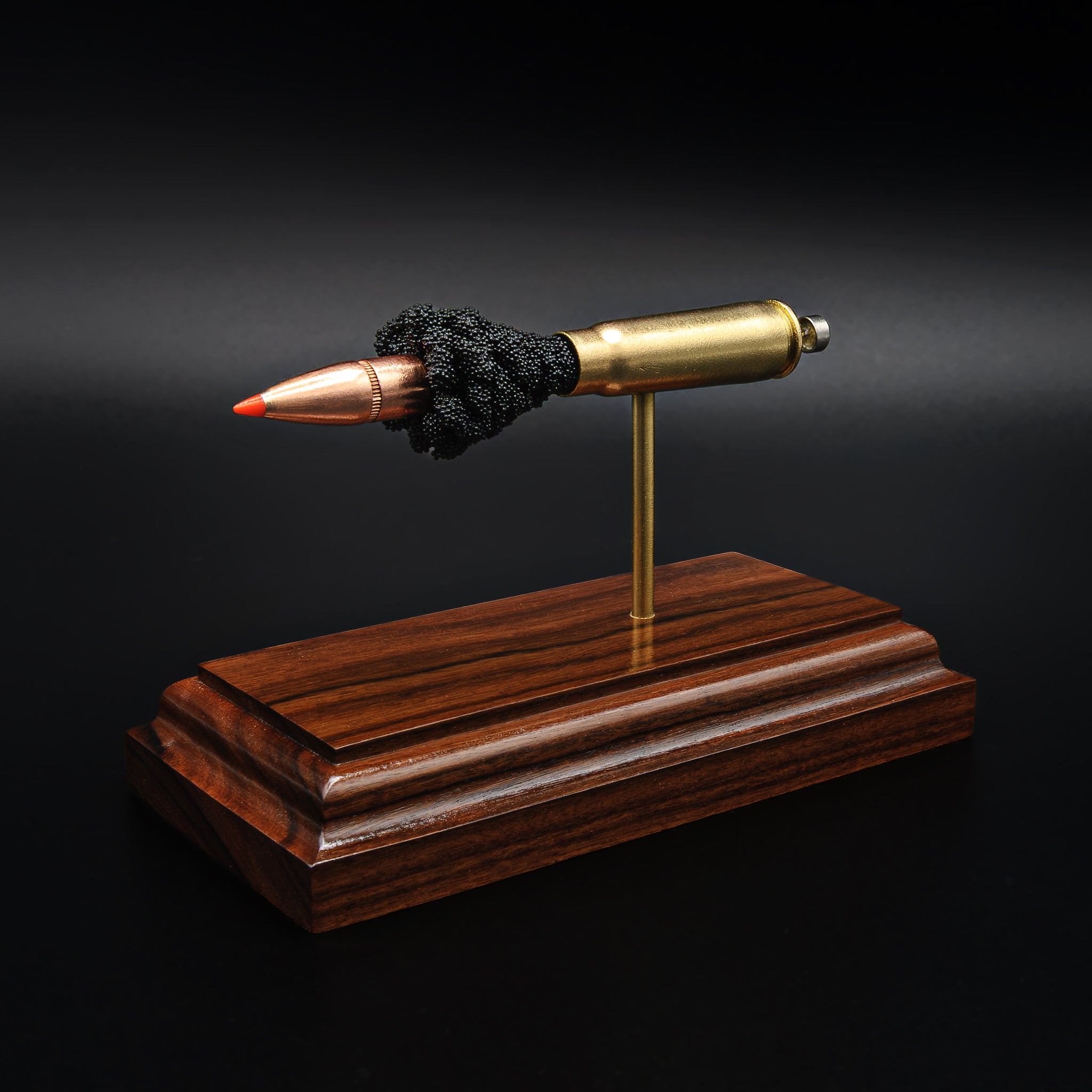 Close-up of a 7.62x39 cartridge model on a rosewood base, focusing on the projectile and the spacing between each component