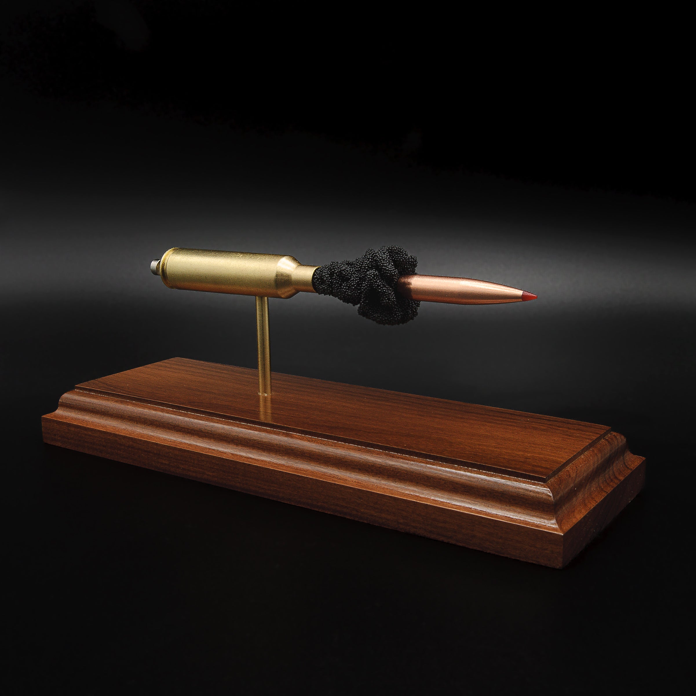 Angled front view of a 7mm PRC Hornady 180gr ELD-M expanded cartridge display on a Bolivian Rosewood base with visible primer cup, anvil, cartridge case, simulated powder, and projectile.