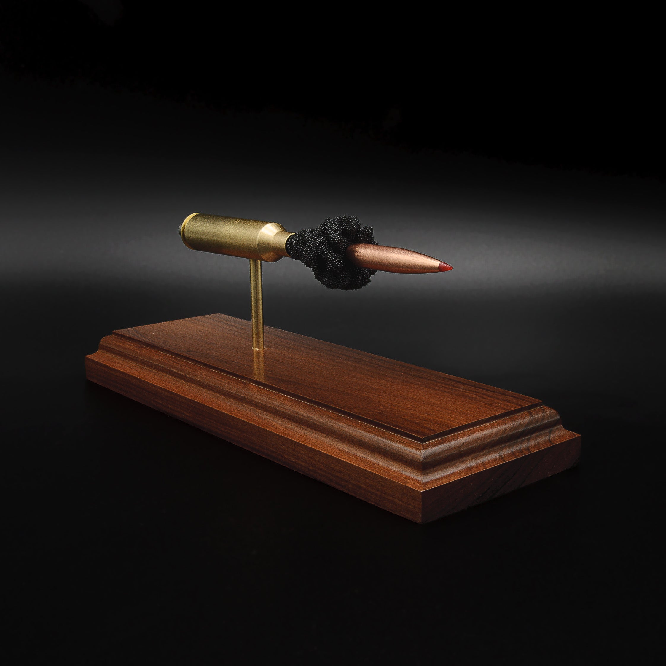 Front three-quarter view of a 7mm PRC Hornady 180gr ELD-M expanded cartridge display mounted on a Bolivian Rosewood base showing the primer cup, anvil, cartridge case, simulated powder, and projectile.
