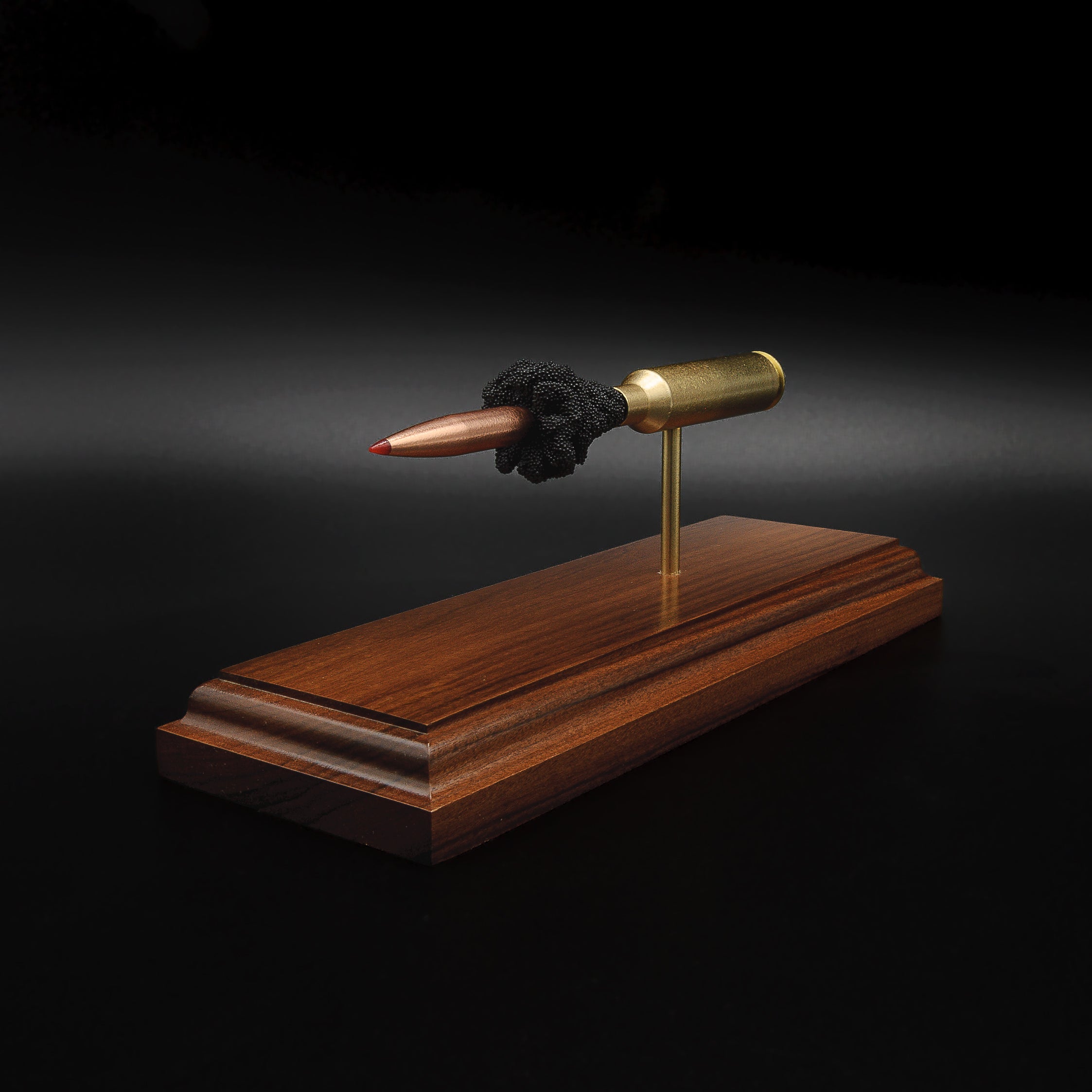 Rear three-quarter view of a 7mm PRC Hornady 180gr ELD-M expanded cartridge display on a Bolivian Rosewood base showing the primer cup, anvil, cartridge case, simulated powder, and projectile.