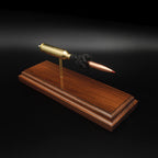 High angle front three-quarter view of a 7mm PRC Hornady 180gr ELD-M expanded cartridge display on a Bolivian Rosewood base with visible primer cup, anvil, cartridge case, simulated powder, and projectile.