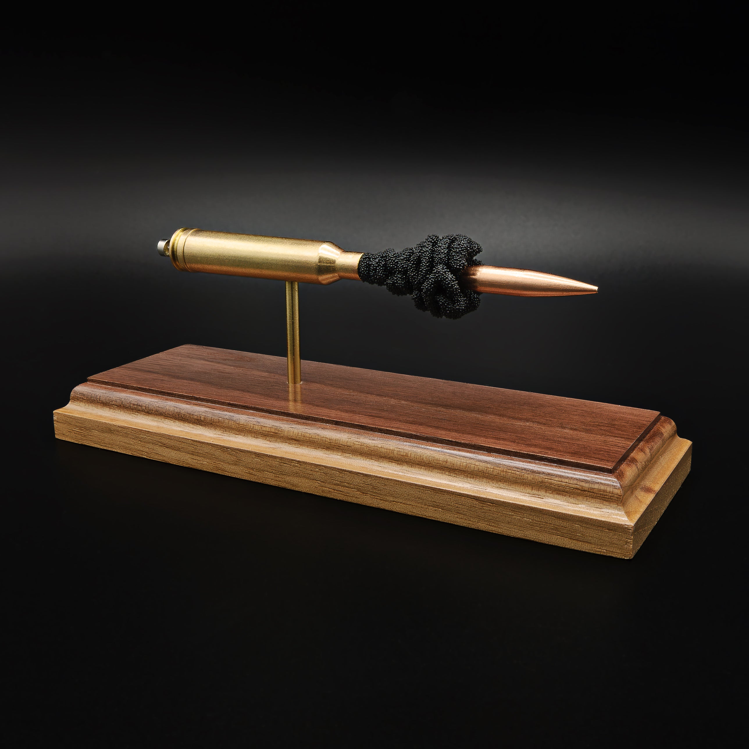 Front-right three-quarter view of a handcrafted 7mm Remington Magnum display showcasing the 168gr Berger VLD bullet, brass case, exposed simulated powder, and walnut wood base.