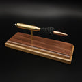 High front-left angle of a handcrafted 7mm Remington Magnum display showcasing the brass cartridge case, 168 grain Berger VLD bullet, exposed simulated powder, and walnut wood base against a black background.