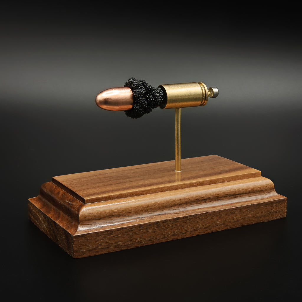 Front angled view of 9mm full metal jacket bullet in exploded cartridge display on walnut base