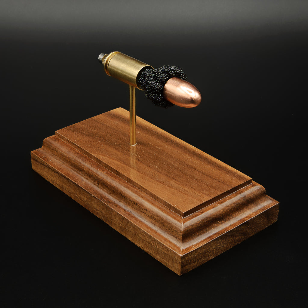 Opposite side view of 9mm Luger cartridge anatomy model with aligned components on walnut base