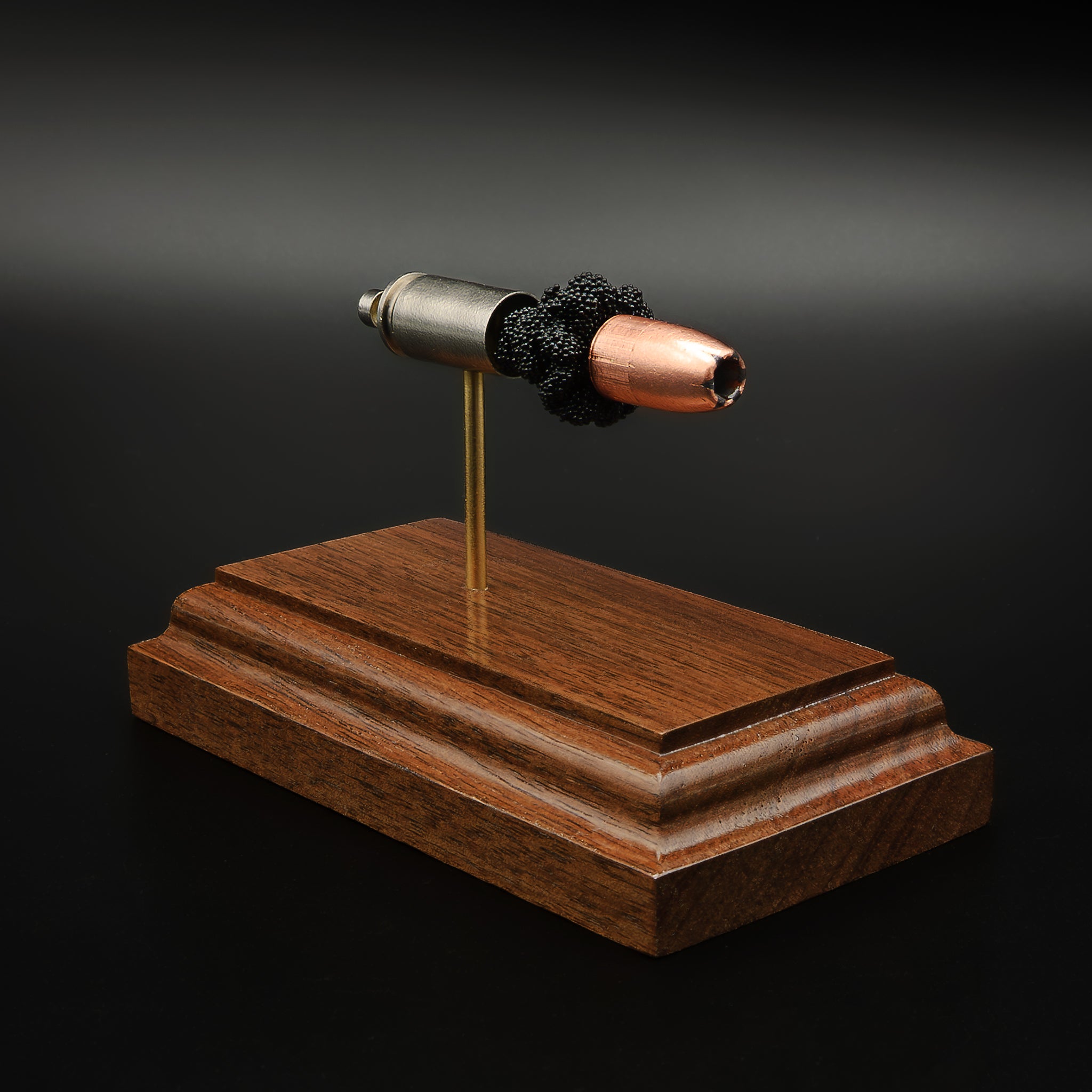 Angled view of 9mm Speer Gold Dot 124gr hollow point cartridge display on walnut base