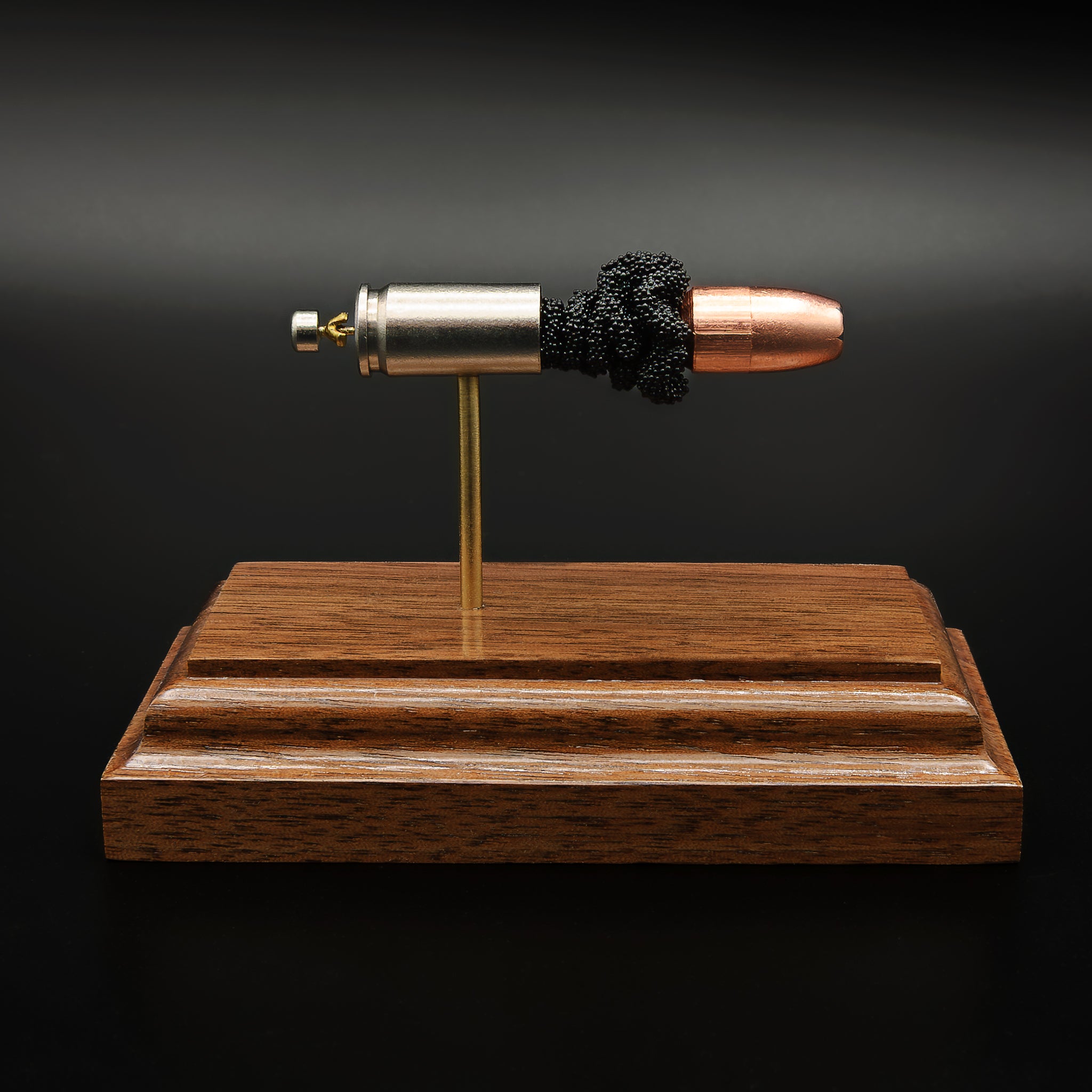 Side profile of 9mm Luger Speer Gold Dot 124gr cartridge anatomy model on walnut base