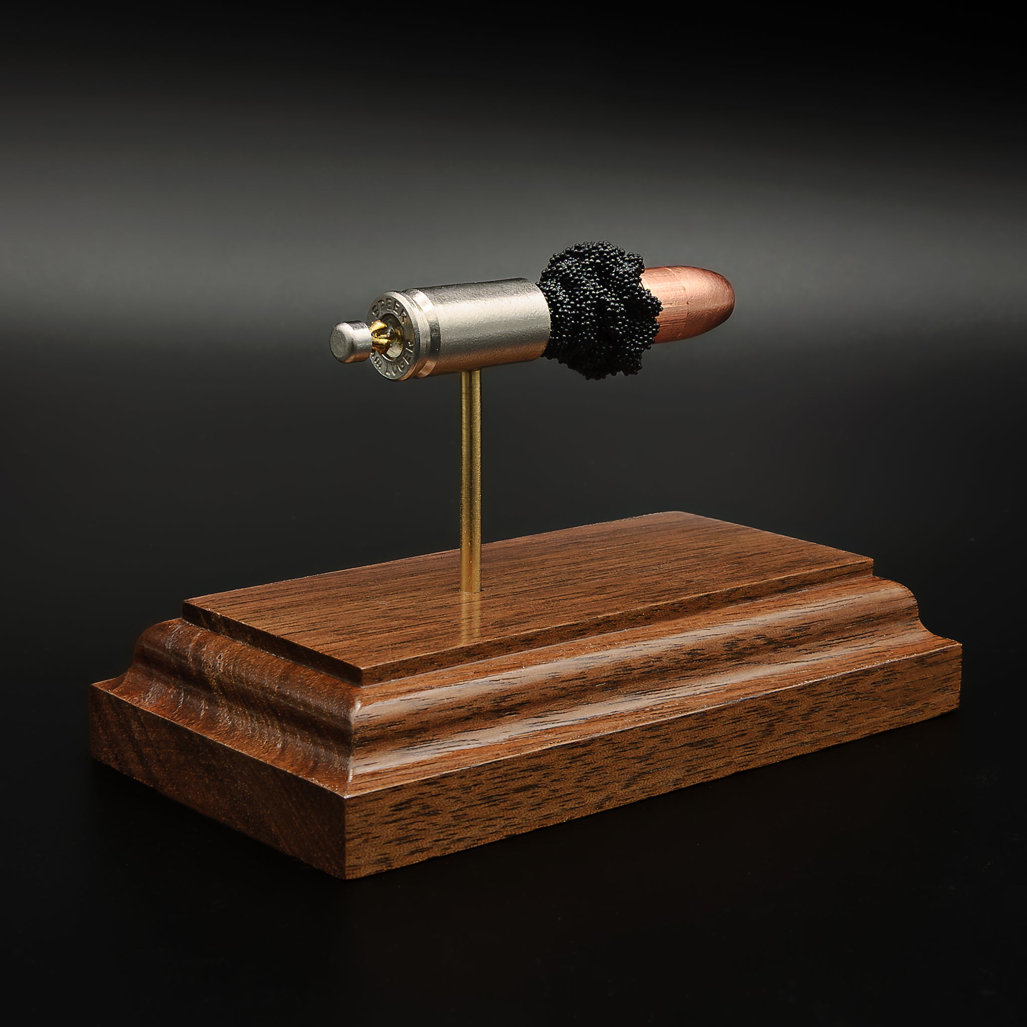 Rear view of 9mm Speer Gold Dot cartridge showing primer and case head on walnut base