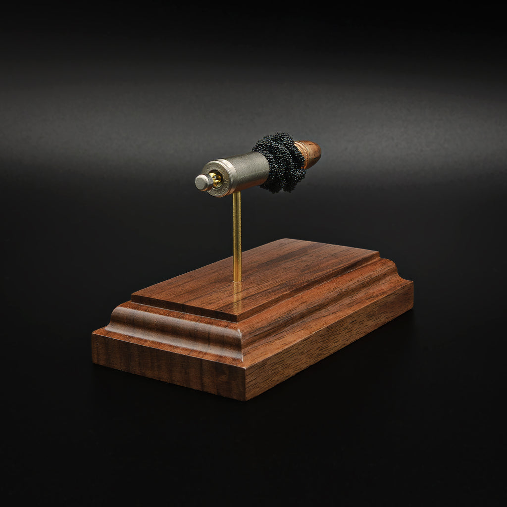 Direct rear view of an inert 9mm Luger display emphasizing the cartridge case head, primer assembly, exposed simulated powder, Federal 147 grain HST hollow point bullet, and handcrafted walnut presentation base.