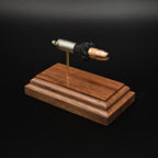 Front-right three-quarter view of an inert 9mm Luger cartridge display highlighting the Federal 147 grain HST hollow point projectile, exposed simulated powder, and handcrafted walnut presentation base.