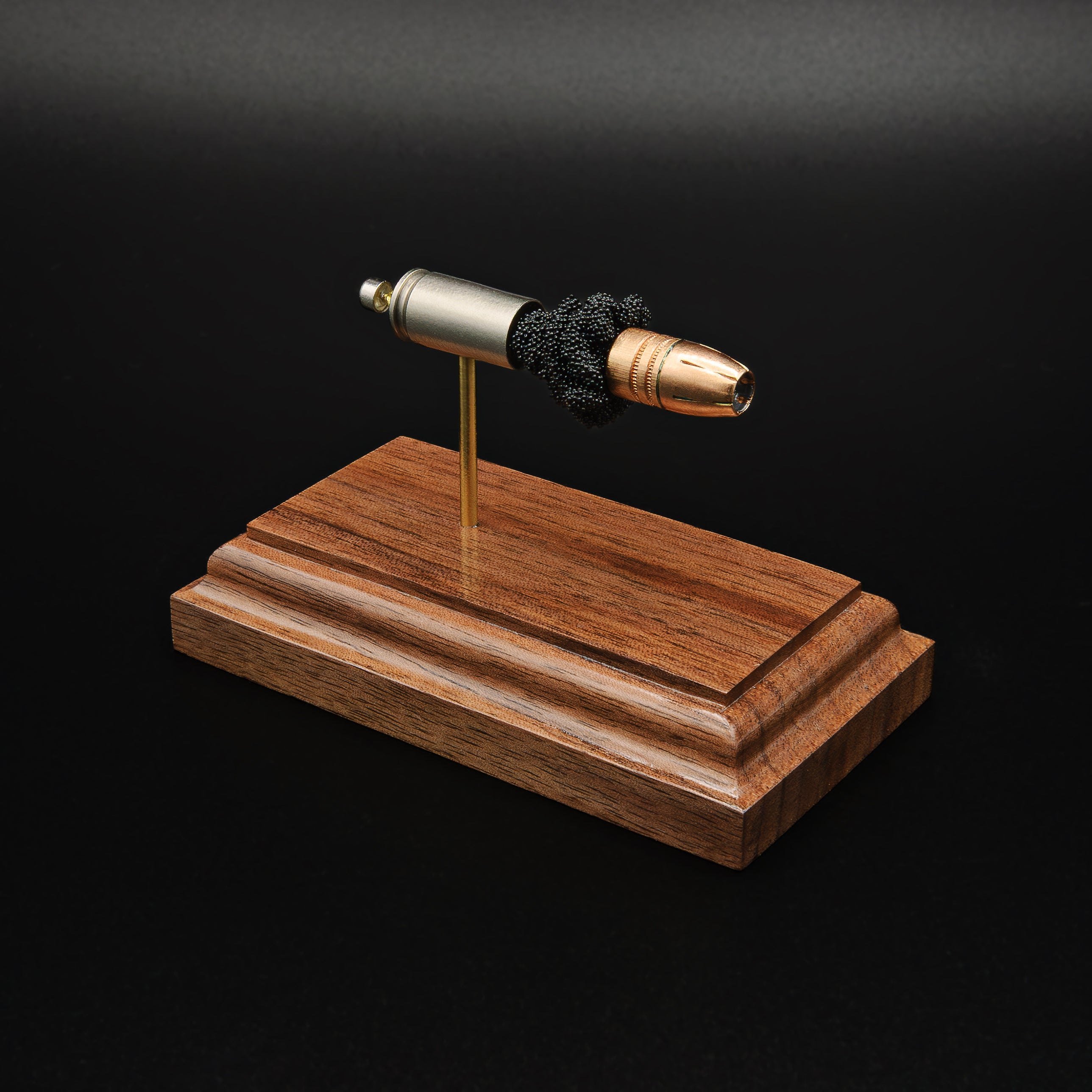 Front-right three-quarter view of an inert 9mm Luger cartridge display highlighting the Federal 147 grain HST hollow point projectile, exposed simulated powder, and handcrafted walnut presentation base.