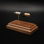 Left-side perspective of an exploded 9mm Luger display featuring a Federal 147gr HST hollow point bullet, nickel-plated case, simulated powder, and solid walnut wood base against a black background.