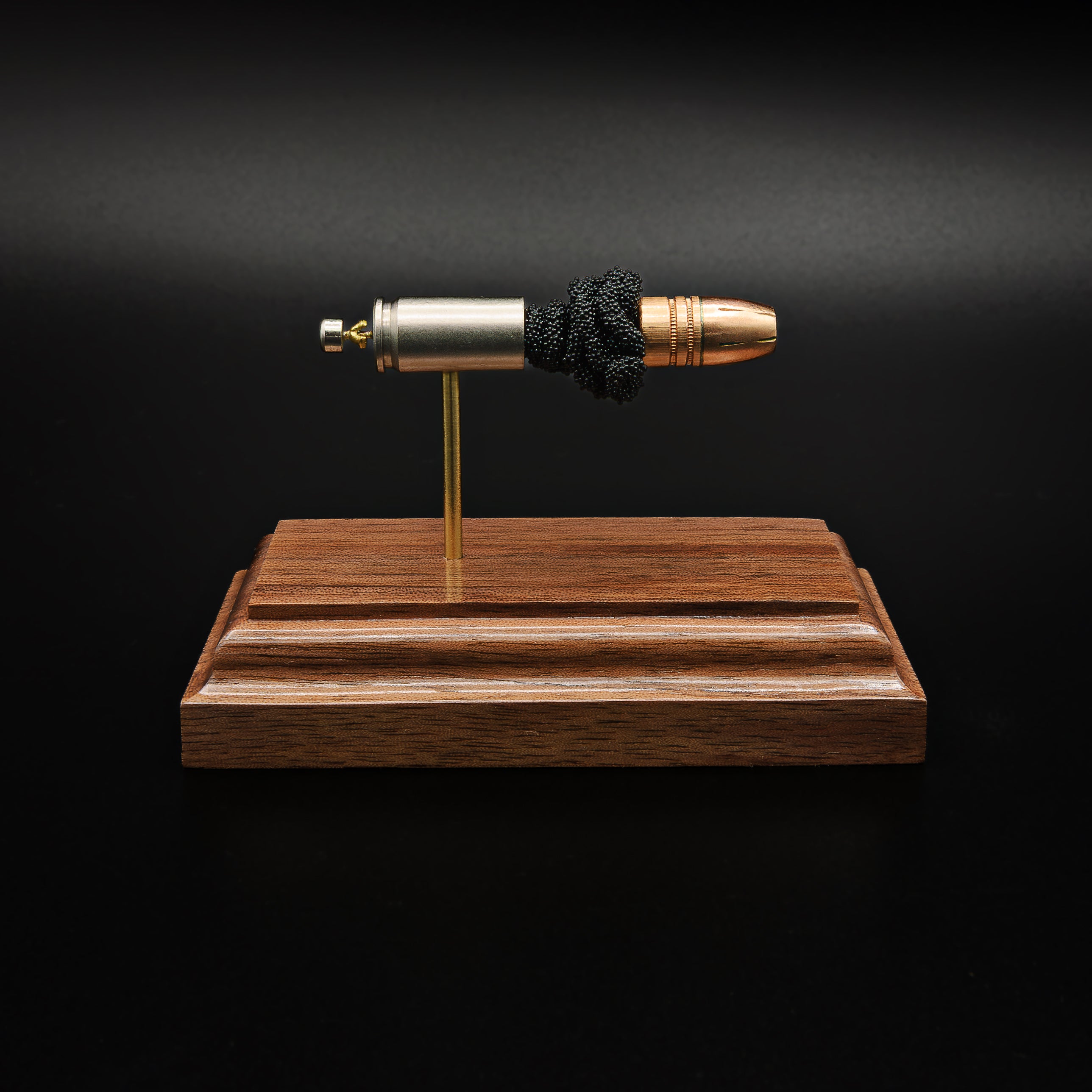 Side profile of a handcrafted 9mm Luger cartridge display with a Federal 147 grain HST hollow point bullet separated from the case by exposed simulated powder and mounted on a walnut presentation base.