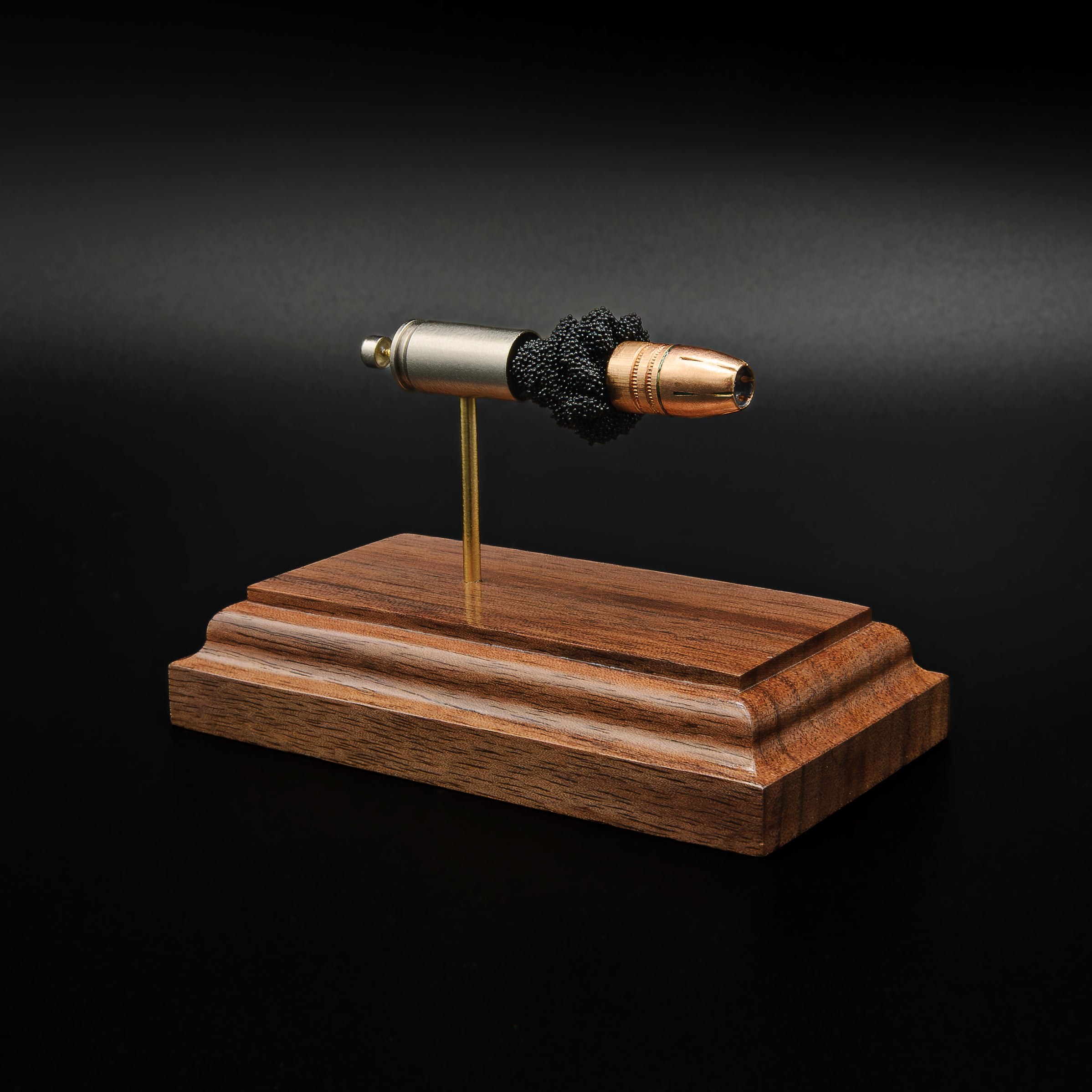 Right-front angle of an exploded 9mm Luger display showcasing the Federal 147gr HST hollow point bullet, exposed simulated powder, nickel-plated case, and handcrafted walnut wood base.