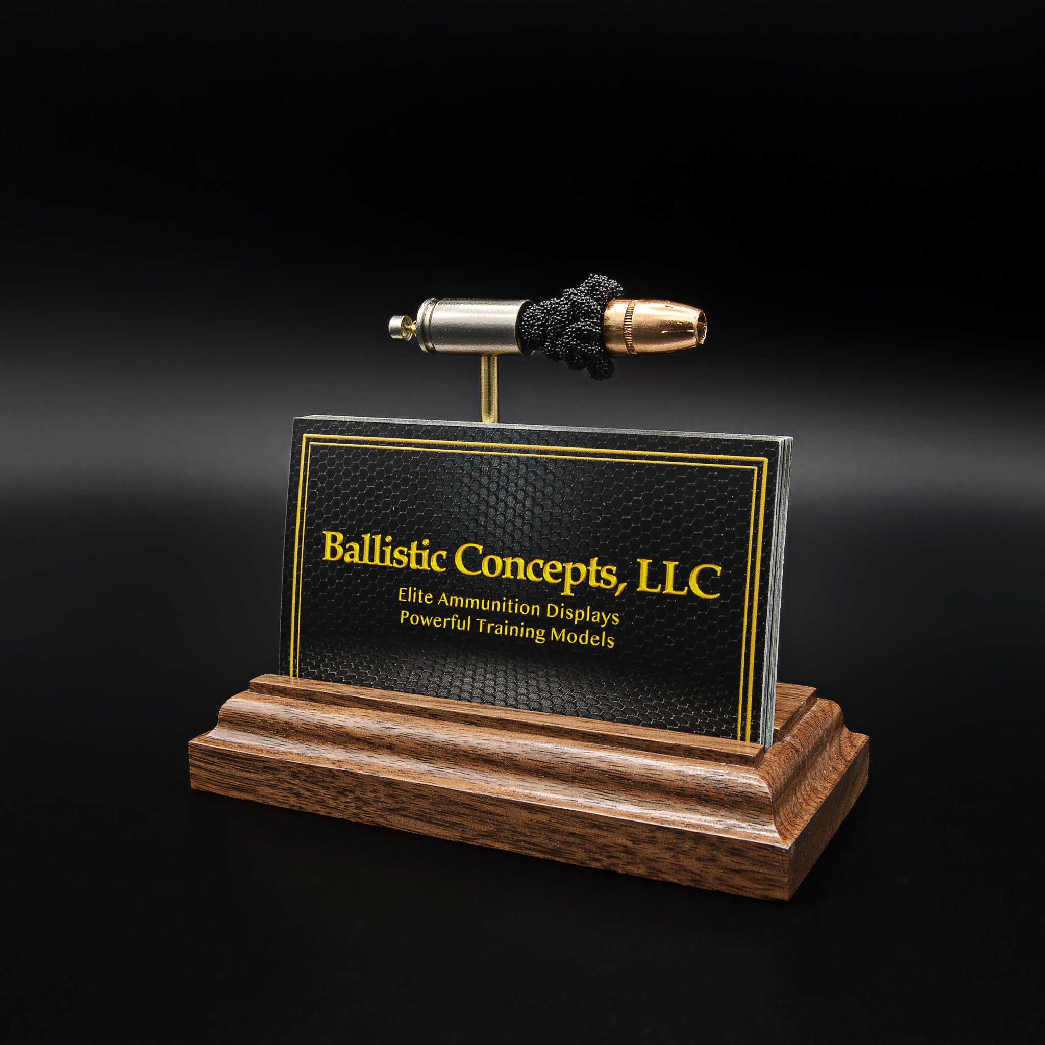 A 9mm Luger cartridge model mounted on a wooden base with a built-in slot holding a stack of business cards