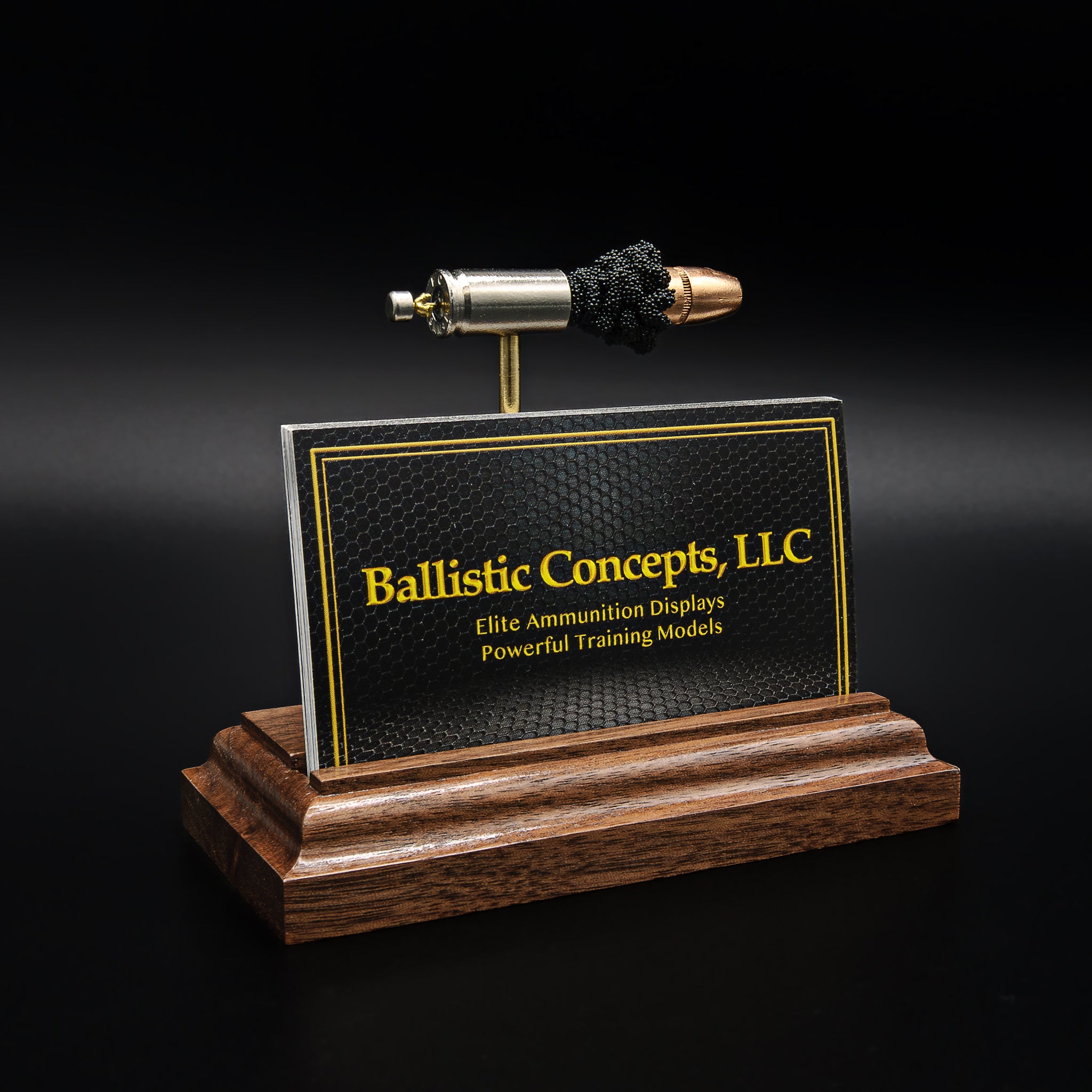 Side view of a 9mm cartridge display on a wood base, with the bullet and casing aligned above a business card holder slot