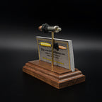Angled view of a 9mm Luger model on a hardwood base, showing the card slot filled with business cards beneath the cartridge