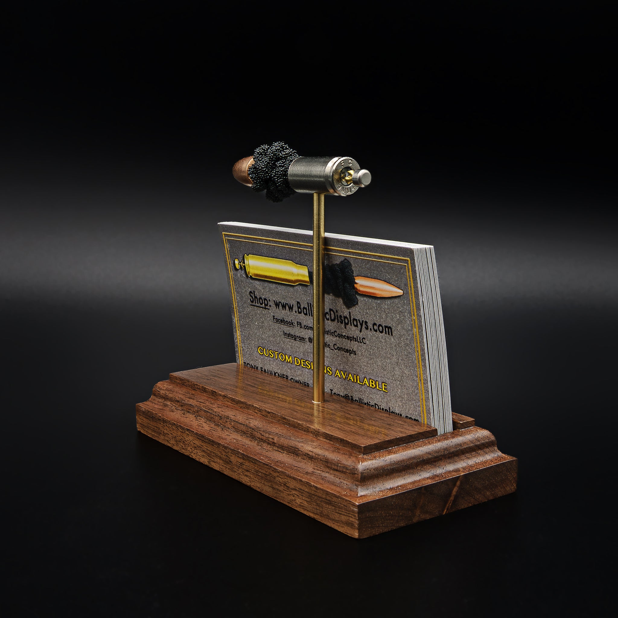 Angled view of a 9mm Luger model on a hardwood base, showing the card slot filled with business cards beneath the cartridge