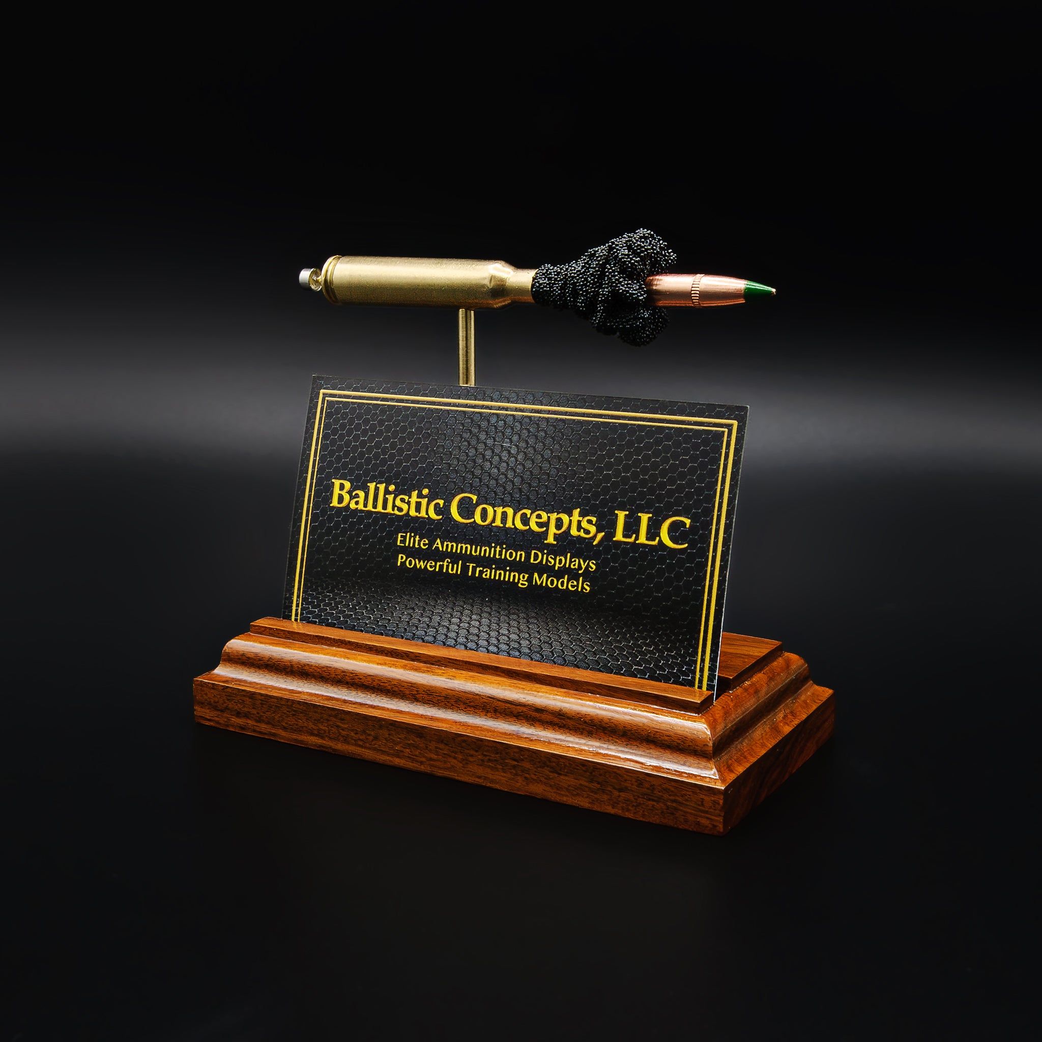 Desk display combining rifle cartridge anatomy model with business card holder slot, crafted from real materials