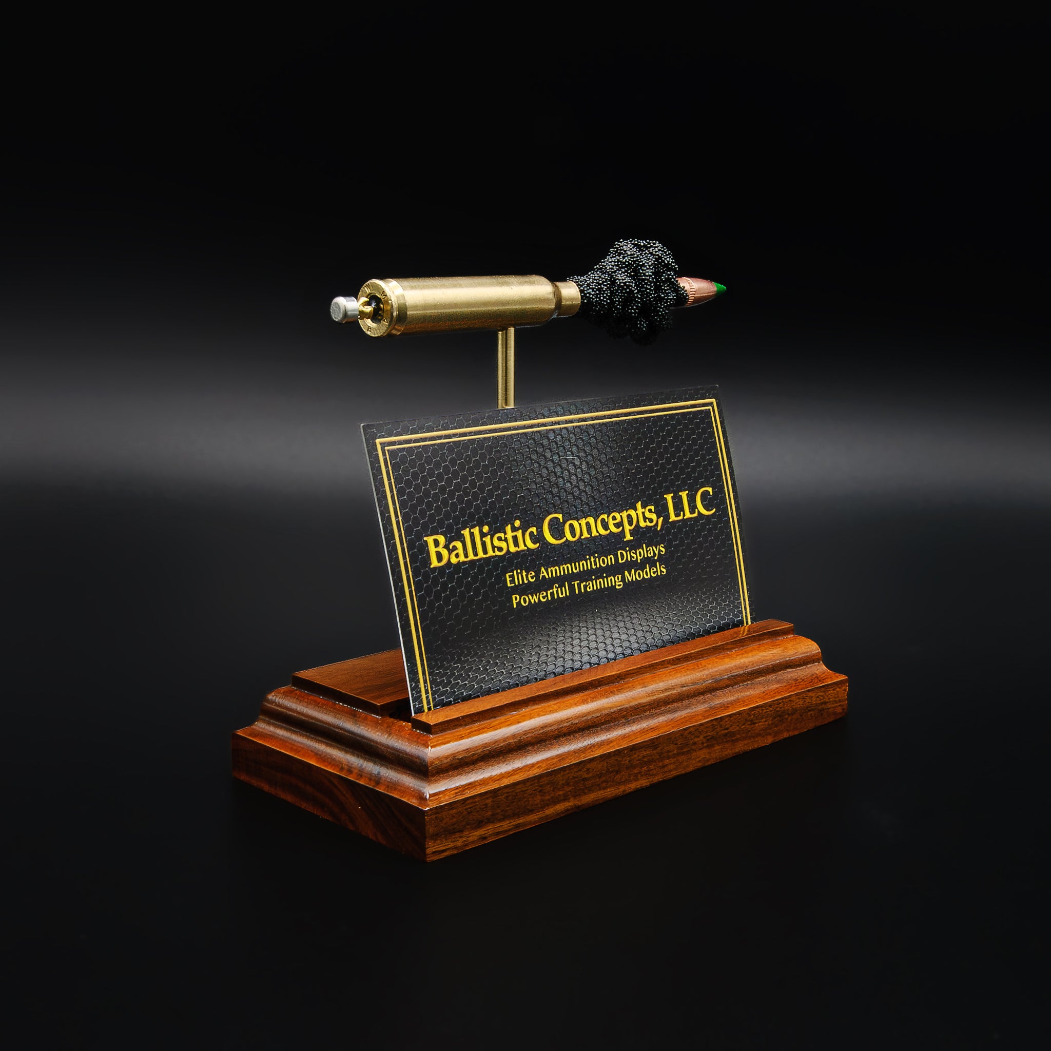 Close view of cartridge-based business card stand showing detailed bullet and casing mounted on finished hardwood base