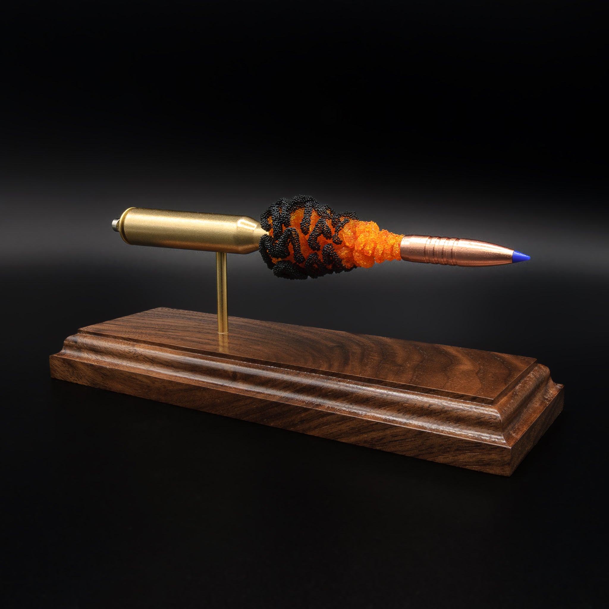 Angled view of 338 Lapua Magnum cartridge anatomy model featuring copper projectile and dynamic powder display on hardwood stand