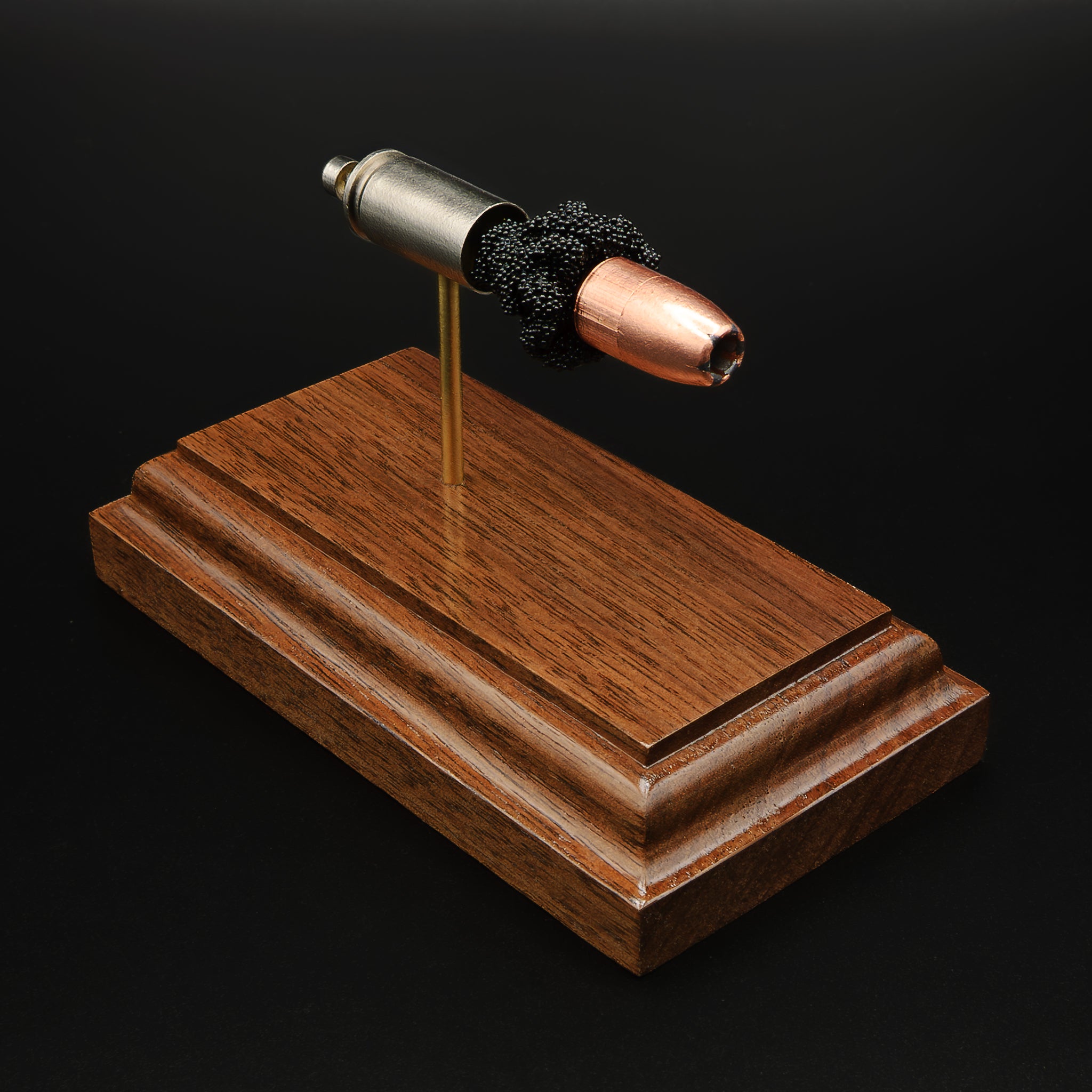 exploded 9mm defensive hollow point cartridge display with Speer Gold Dot bullet on walnut base