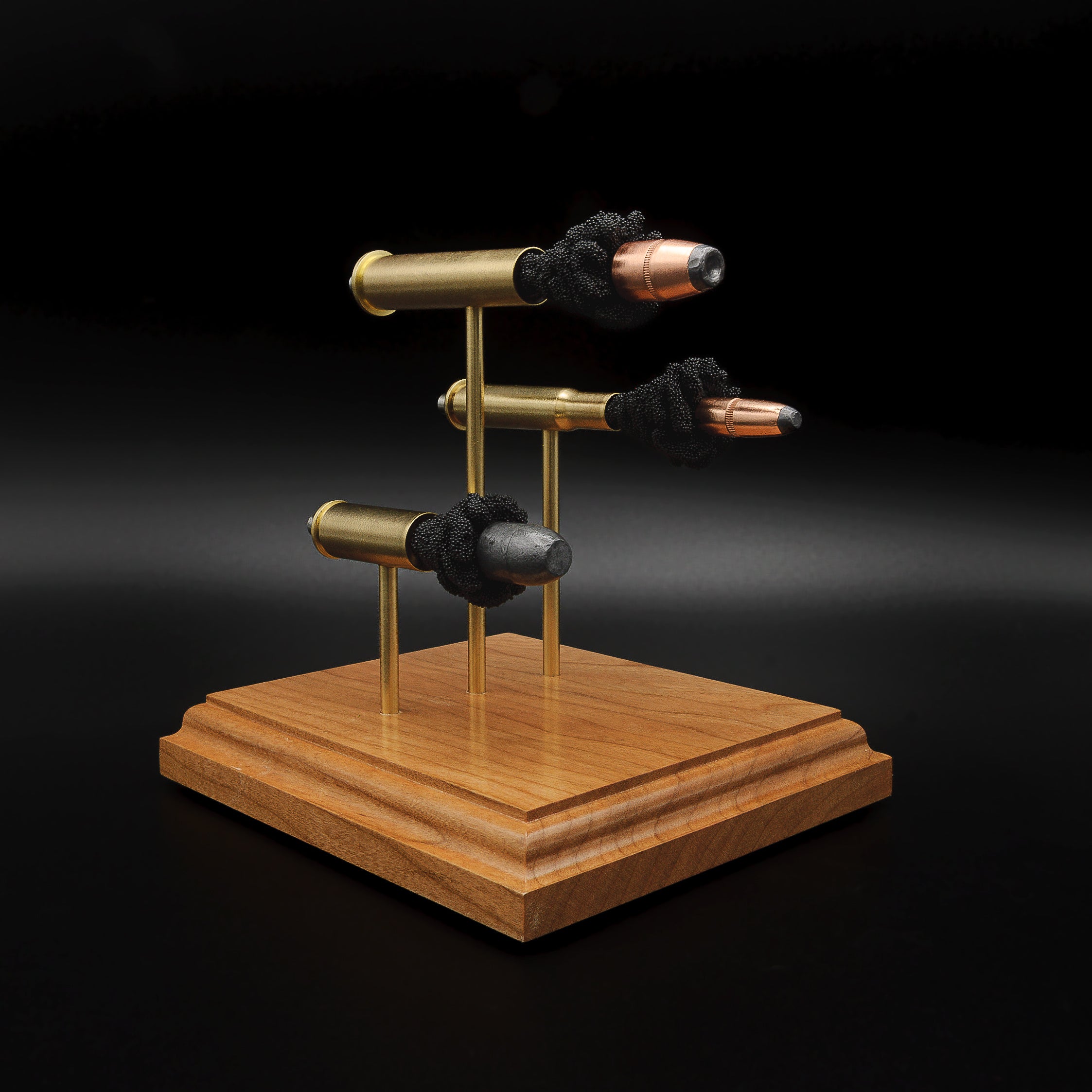 Angled view of the triple cartridge anatomy display featuring 45-70 Government, 30-30 Winchester and 45 Colt components mounted on a cherry base.