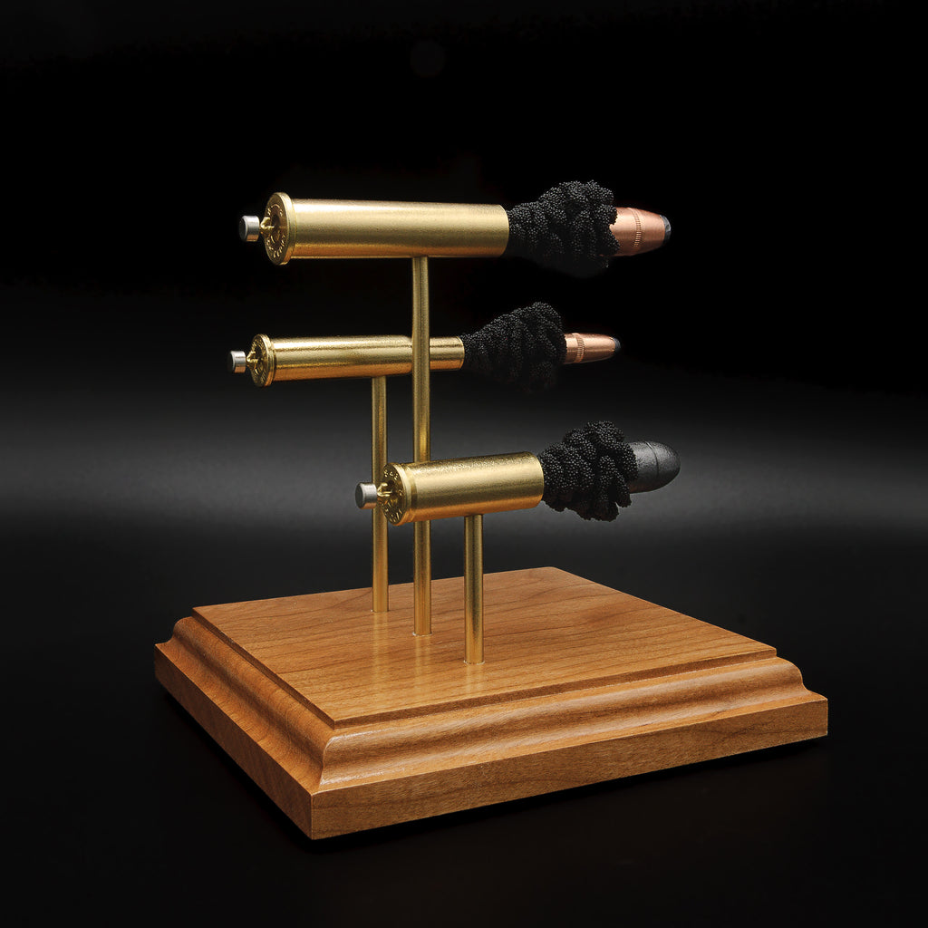 Side view of the triple-caliber cartridge display showing primer cups, anvils, cartridge cases, simulated powder and projectiles mounted on cherry.