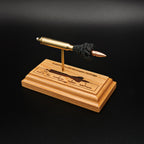 Three-quarter view of a .223 Remington FMJ cartridge anatomy display showing the primer cup, anvil, cartridge case, simulated powder, and projectile on a cherry wood base with an engraved anatomy diagram.
