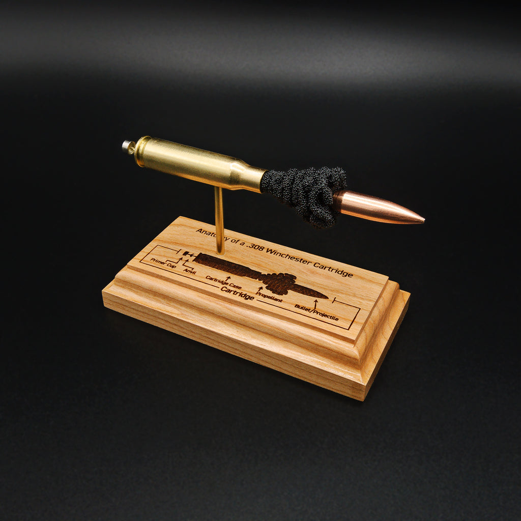 Overhead angle of a handcrafted .308 Winchester exploded cartridge display with a 168gr Sierra MatchKing HPBT bullet and detailed engraved anatomy diagram on a solid cherry wood base.