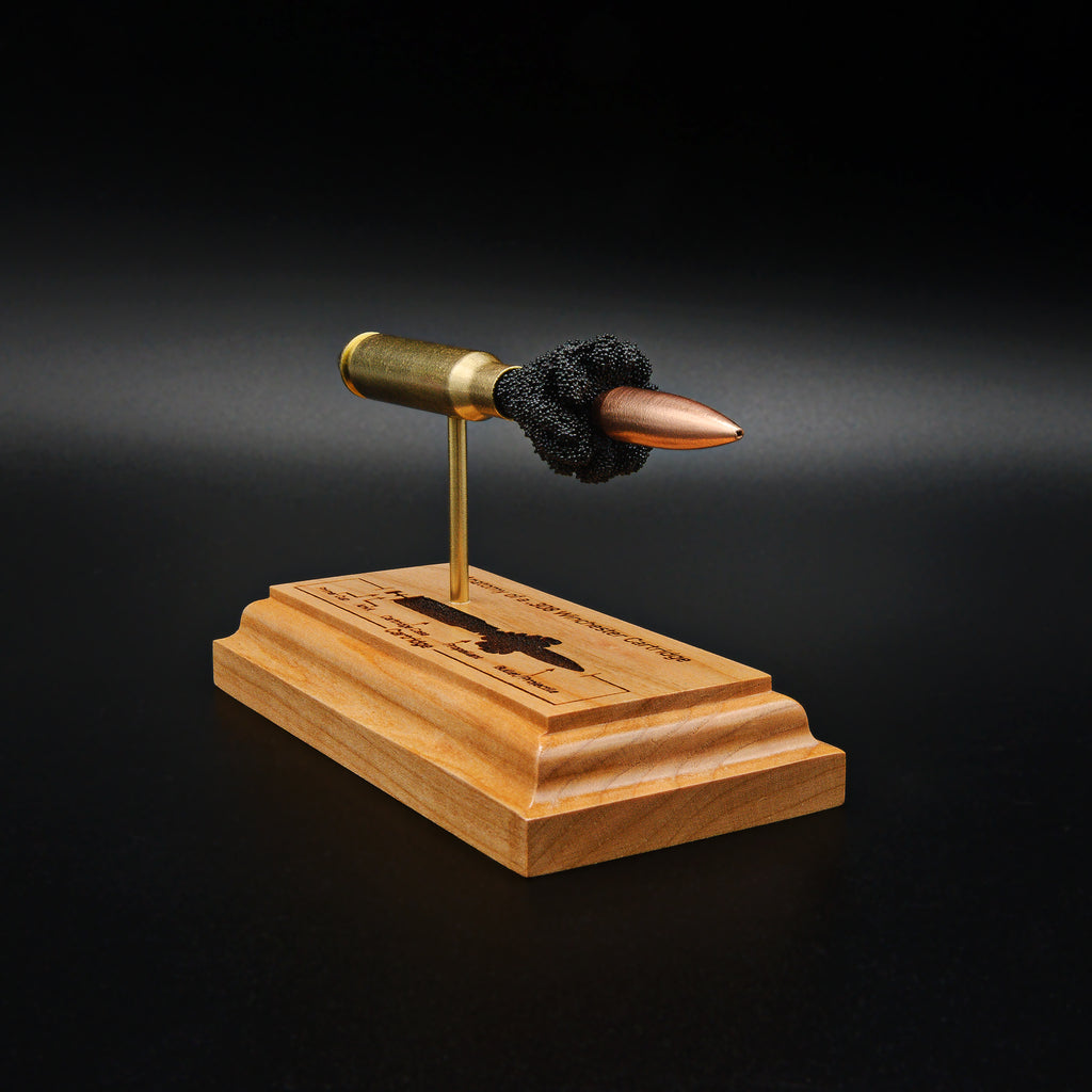 Left side view of a .308 Winchester cartridge display highlighting the 168gr Sierra MatchKing HPBT bullet, exposed cartridge components, and engraved anatomy diagram on a cherry wood base.