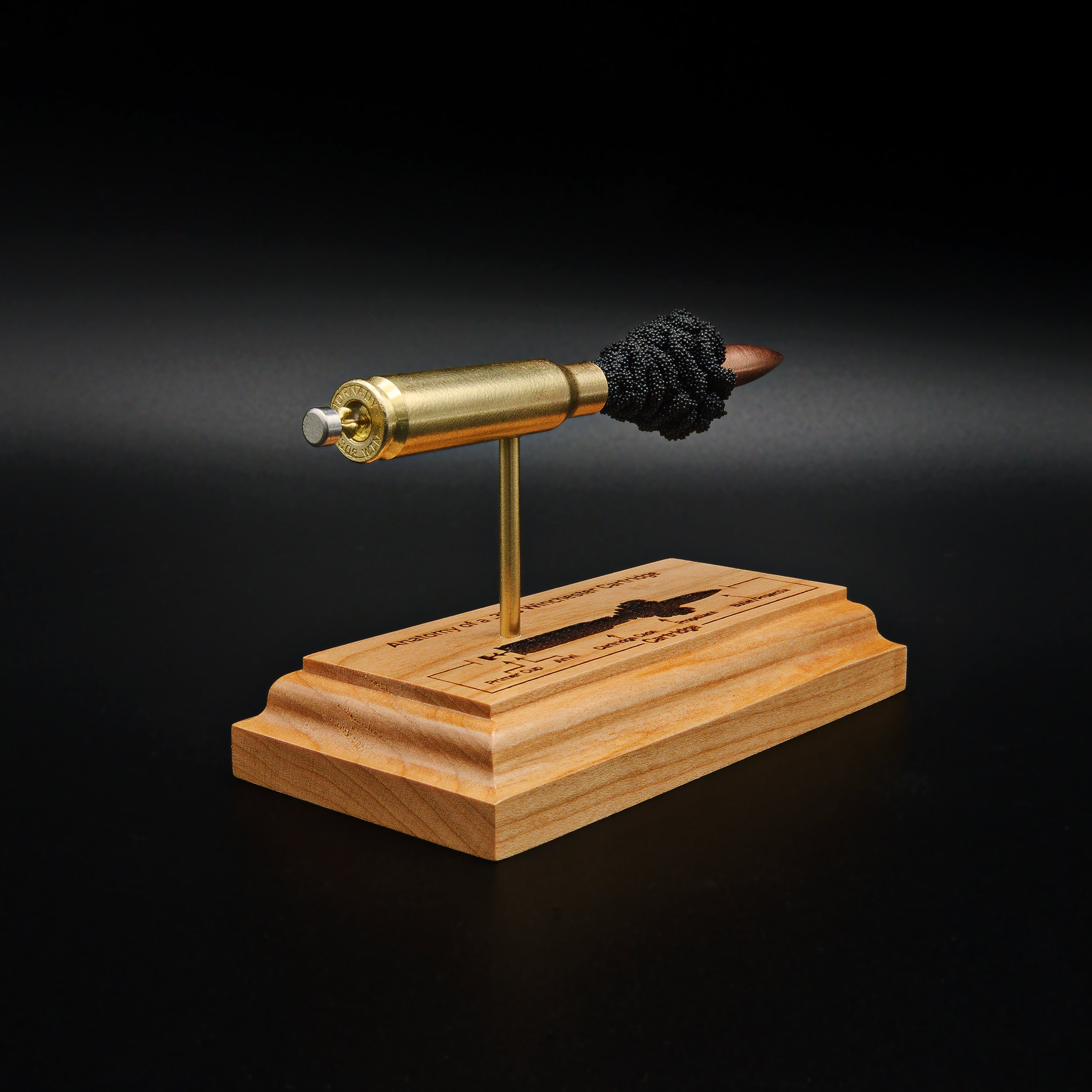 Rear three-quarter view of a .308 Winchester exploded cartridge display with a 168gr Sierra MatchKing HPBT bullet and engraved educational anatomy diagram on a premium cherry wood base.